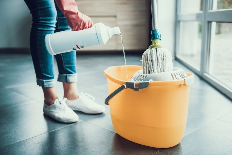 A person pouring cleaning liquid into a mop's bucket