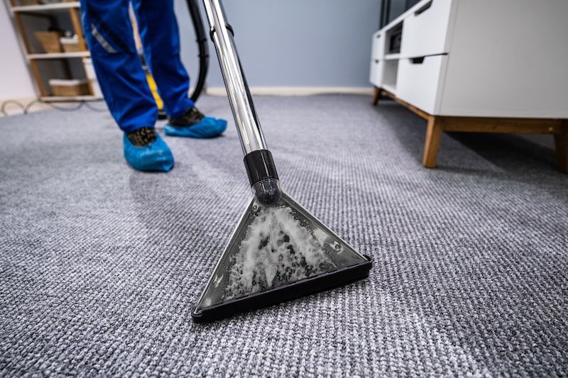 A person vacuuming the floor mat
