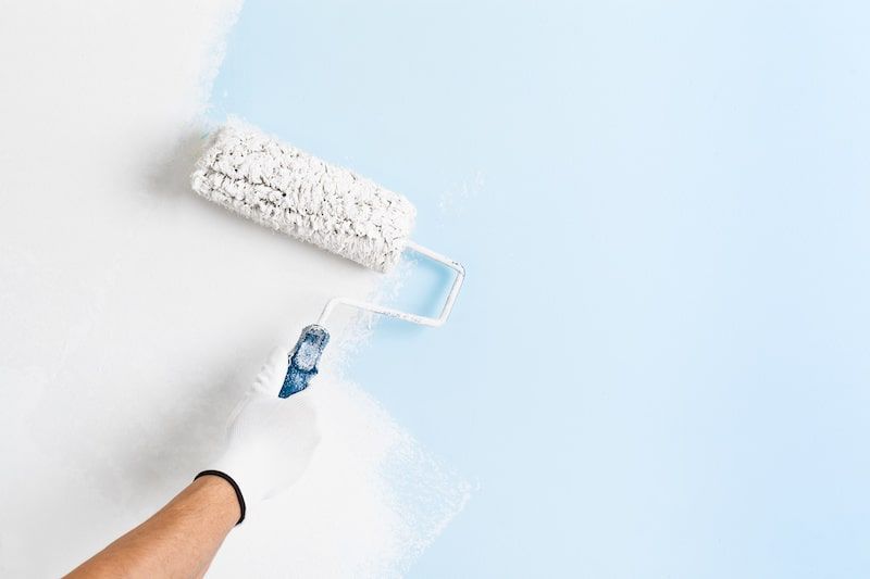 roller being used to paint a white wall