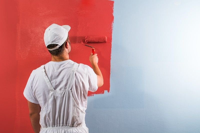 man painting a wall red