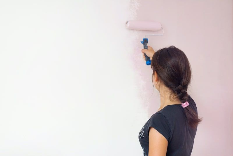 woman painting a wall pink