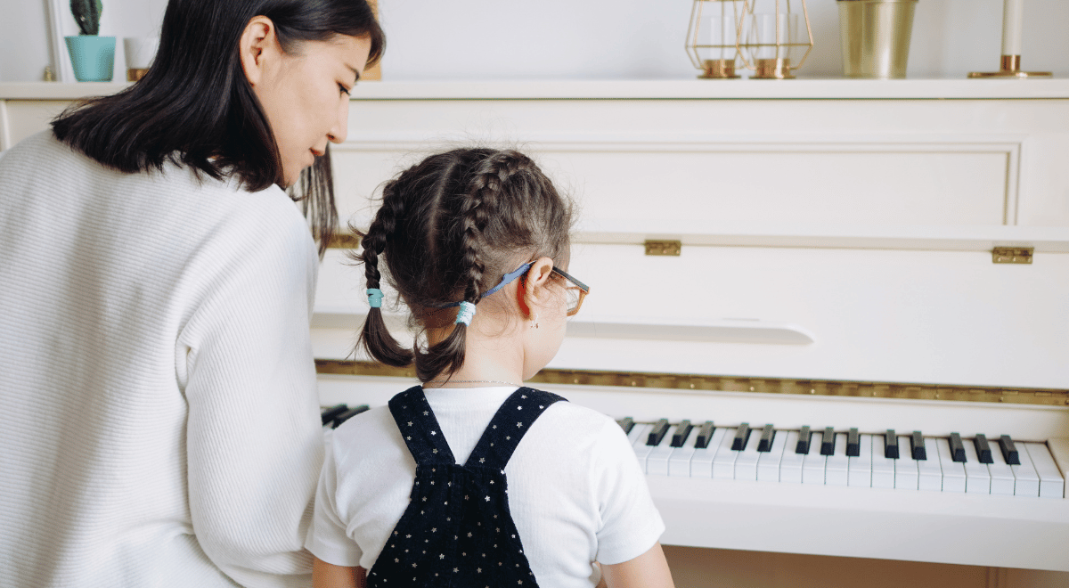 Mother teaching her daughter how to play piano