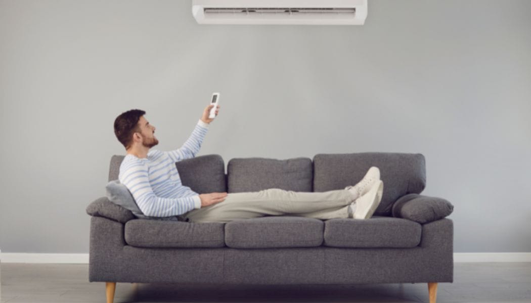 A man using the AC while lying on a sofa