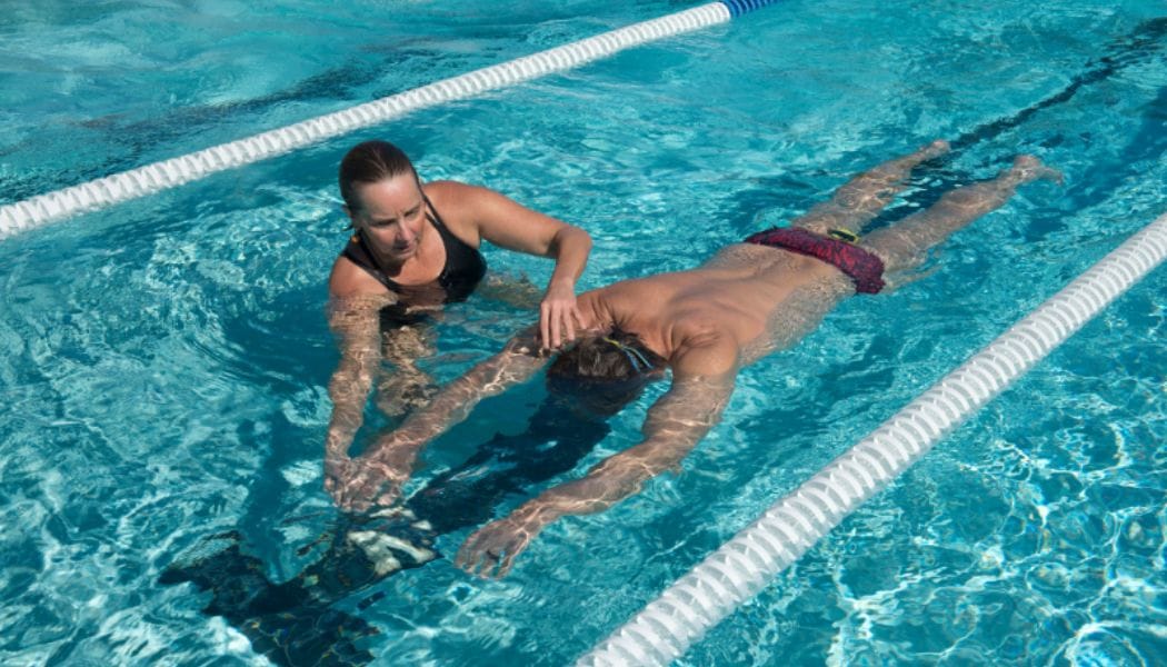 A swimming instructor helping a person swim