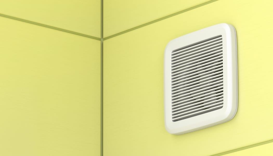 An exhaust fan fit into a yellow wall