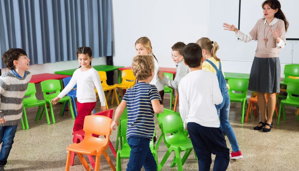 Children playing musical chairs supervised by an adult