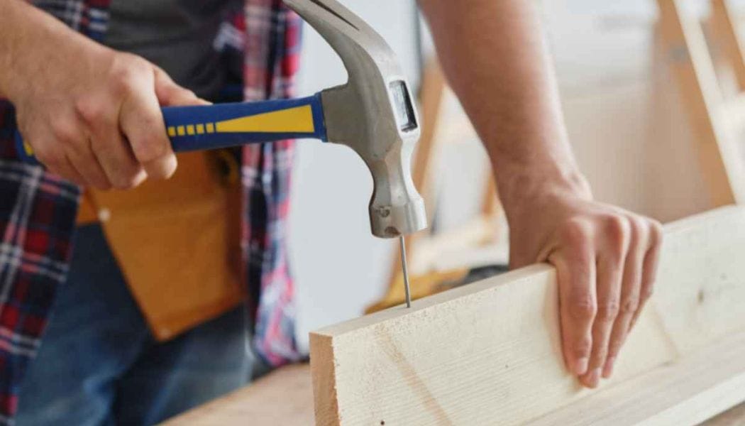 man hitting a nail with a claw hammer