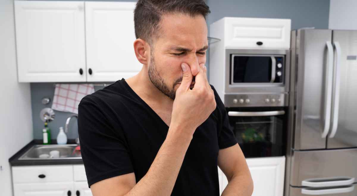 man holding nose due to kitchen odor