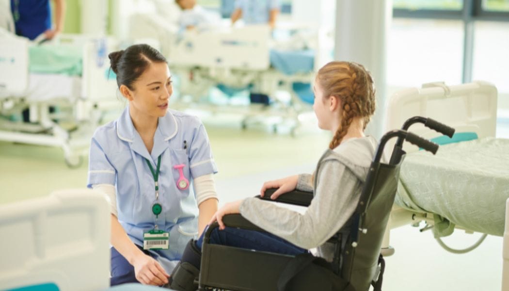 A nurse taking care of a girl in a wheelchair