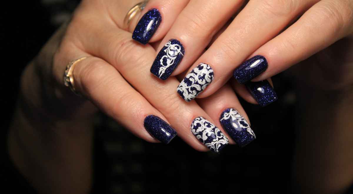 blue glittery nails with white design 