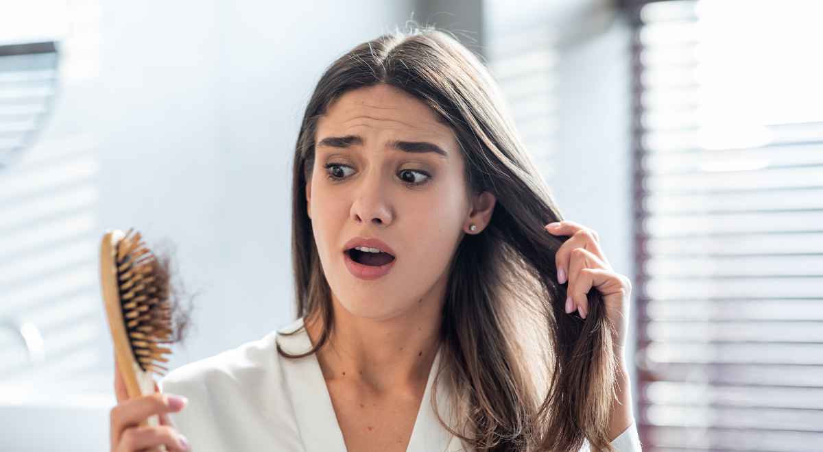 woman frustrated looking at her fallen hair and comb