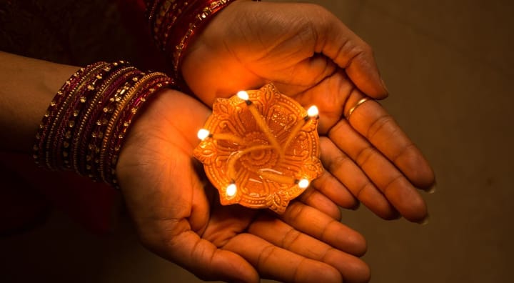 A picture of the hands of a woman holding a diya