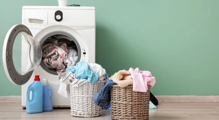 Washing machine with two laundry baskets full of clothes in front