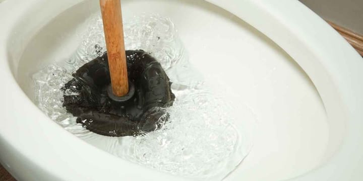 Fixing a clogged toilet with a plunger