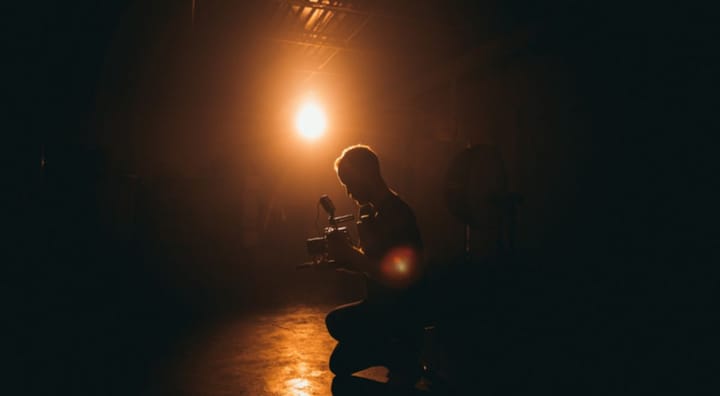 Man kneeling, taking a picture in dim lighting