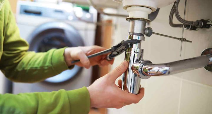 Image of a person fixing plumbing equipment in a newly constructed house