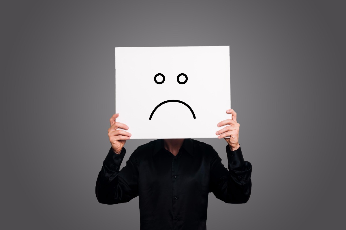 man holding a sad face placard