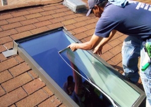 man cleaning a window on a roof
