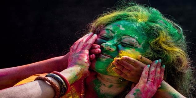 people rubbing holi colors on a woman's face