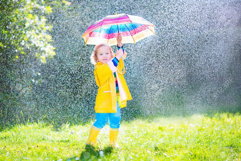 little girl in yellow raincoat holding up a colourful umbrella in the rain