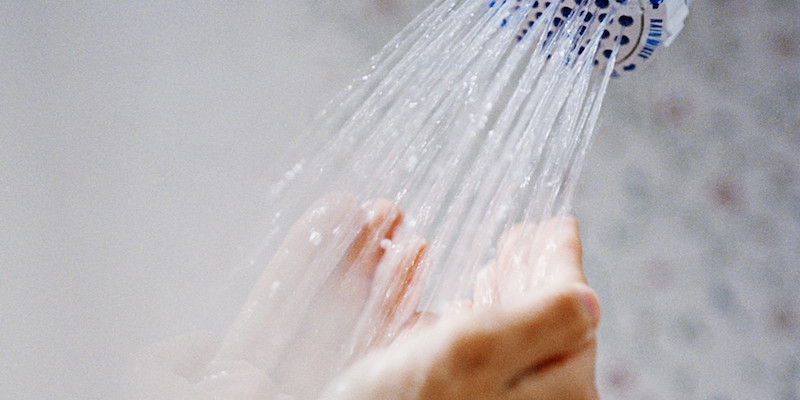 pair of hands cupped to collect water running from a shower