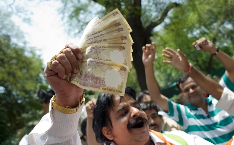 man holding a bundle of 500 rupee notes