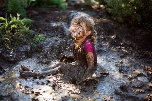 kid sitting in a dirt puddle splashing dirt