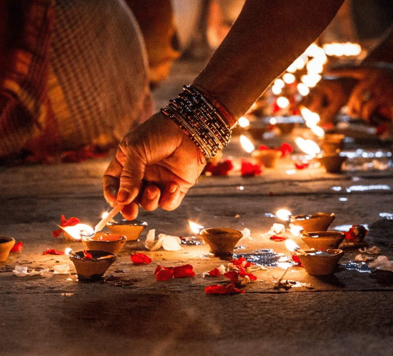 woman lighting a diya with a candle