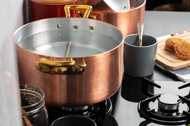 a copper casserole with water on a gas stove